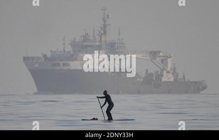 © lizenziert für London News Pictures. 29/11/2020. Swansea, Großbritannien. Ein Paddelboarder ist im Meer abgebildet, das an einem Schiff vor der Küste von Swansea vorbeifährt, am Ende eines schönen Tages in Wales und quer durch Großbritannien. Foto: Robert Melen/LNP Stockfoto