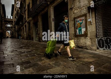 Barcelona, Spain. 18th Dec, 2020. A commuter walks past a graffiti by Italian urban artist 'TVBoy', Salvatore Benintende, titled 'Feliz Sanidad' (merry health) depicting a COVID-19 vaccine delivering Santa Claus changing the word 'navidad' into 'sanidad' (Christmas > health) as the first COVID-19 vaccinations are announced for December 27th Credit: Matthias Oesterle/Alamy Live News Stock Photo