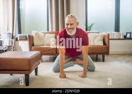 Grauhaariger, gut aussehender Mann, der Yoga macht und sich gut fühlt Stockfoto