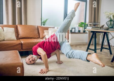 Grauhaariger, gut aussehender Mann, der Yoga macht und sich gut fühlt Stockfoto