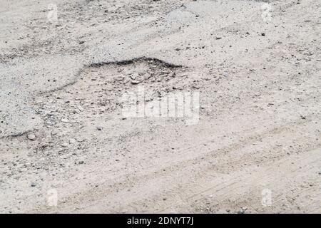 Schlagloch in einem Parkplatz am Meer. Konzept Unebener Untergrund, schlechte Wartung, kaputte Infrastruktur, schlechter Job, raue Straße voraus. Stockfoto