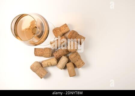 Glas Roséwein mit verstreuten gebrauchten Korken auf Weiß Hintergrund in der Draufsicht Stockfoto