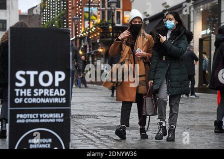 Die Leute laufen an einem Schild vorbei, das in Covent Garden in London soziale Distanzierungen anweist. Stockfoto