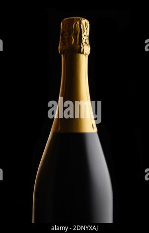 Nahaufnahme einer ungeöffneten Flasche Champagner vor schwarzem Hintergrund. Stockfoto