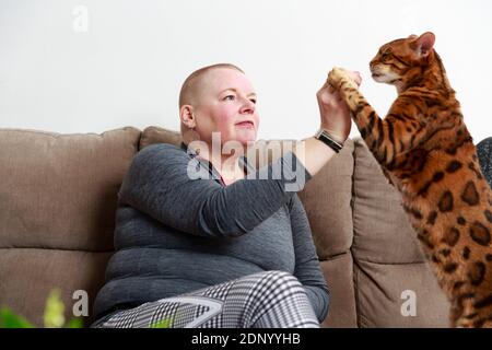 Frau spielt mit Katze auf dem Sofa Stockfoto