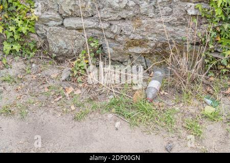 Leere Plastikflaschen und andere Plastikverpackungen für Lebensmittel, die in einer kleinen Seitenstraße in der kornischen Stadt liegen. Konzept der Umweltverschmutzung. Stockfoto