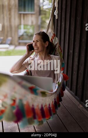 Frau in der Hängematte, die über das Handy spricht Stockfoto