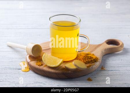 Energy Tonic Drink mit Kurkuma, Ingwer, Zitrone und Honig auf einem Holzbrett, selektiver Fokus Stockfoto