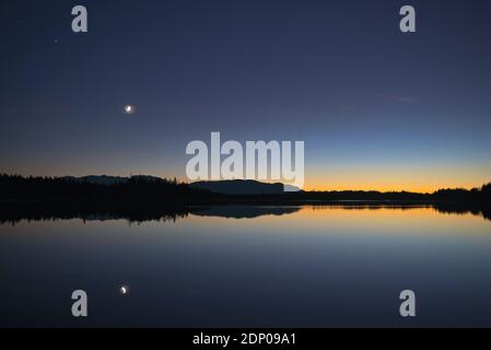 Wachende Mondsichel Spiegelung im Kirchsee in der Abenddämmerung, Bayern, Deutschland Stockfoto