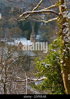 Schneebedeckte Bäume und Kirche der Heiligen Dreifaltigkeit von Lovers aus gesehen Wandern Sie durch eine hohe Felswand im Matlock Bath Derbyshire Peak Distrikt England, Großbritannien Stockfoto