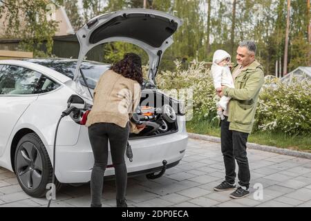 Eltern laden Kinderwagen in Kofferraum Stockfoto