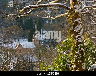 Schneebedeckte Bäume und Kirche der Heiligen Dreifaltigkeit von Lovers aus gesehen Wandern Sie durch eine hohe Felswand im Matlock Bath Derbyshire Peak Distrikt England, Großbritannien Stockfoto