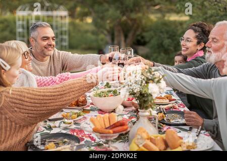Familie Toasten während der Mahlzeit im Garten Stockfoto