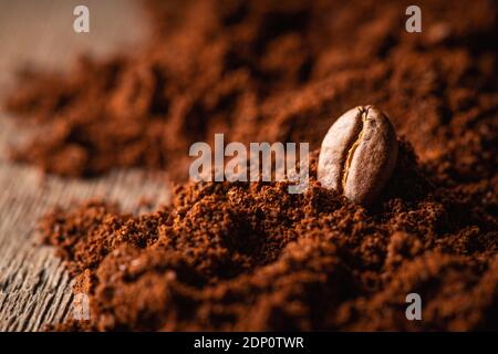 Geröstete Kaffeebohne auf dem Hügel des gemahlenen Kaffees. Makroaufnahme. Kaffeethema. Selektiver Fokus. Geringe Schärfentiefe. Stockfoto