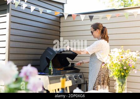 Frau, die Zubereitung von Speisen auf dem Grill Stockfoto