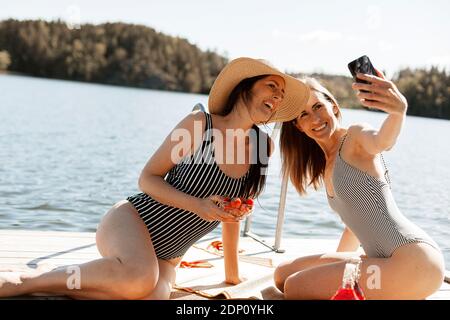 Glückliche Freundinnen, die Selfie auf dem Steg machen Stockfoto