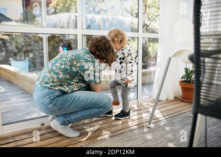 Mutter hilft Tochter Schuhe an Stockfoto