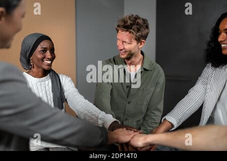 Kollegen verbinden ihre Hände in Huddle Stockfoto