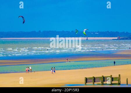 Sommertag auf Camber Sands bei Ebbe mit Familien, die Spaß haben und Kitesurfer.schöner Strand, Sand & Steine, ideal für Familie, Hunde & Wassersport Stockfoto