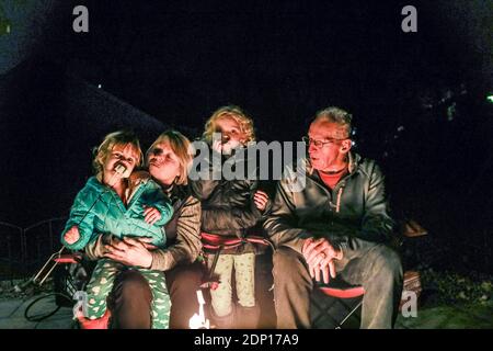 Großeltern sitzen mit Enkeln um Feuergrube herum Stockfoto