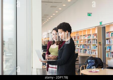 Frauen in der Bibliothek mit Laptop Stockfoto