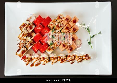 Japanische Sushi-Sets auf weißem Teller und schwarzem Hintergrund Stockfoto