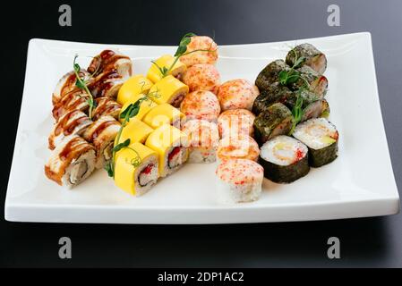 Japanische Sushi-Sets auf weißem Teller und schwarzem Hintergrund Stockfoto