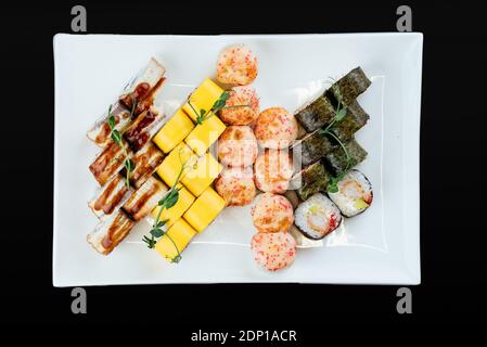 Japanische Sushi-Sets auf weißem Teller und schwarzem Hintergrund Stockfoto