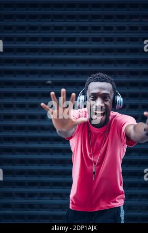 Portrait of excited man wearing pink t-shirt listening to music with headphones Stock Photo