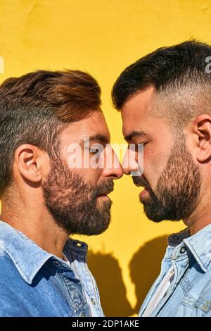 Gay paar stehen von Angesicht zu Angesicht gegen gelbe Wand Stockfoto