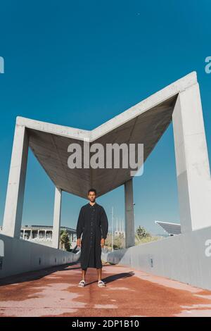 Junger Mann mit schwarzem Kaftan, der auf einer Fußgängerbrücke steht Stockfoto