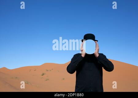 Marokko, Merzouga, Erg Chebbi, Mann, eine Melone holding Spiegel vor sein Gesicht in der Wüste Düne Stockfoto