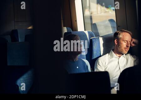 Man sitting in train with eyes closed Stock Photo