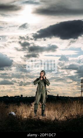 Man posiert als Astronaut auf einer Wiese mit dramatischen Wolken im Hintergrund gekleidet Stockfoto