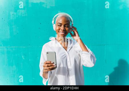 Schöne Frau, die vor der Teelwand steht, Musik hört und Selfies nimmt Stockfoto