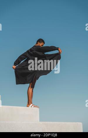 Junger Mann, der schwarze Kaftan trägt, tritt im Freien auf Stockfoto