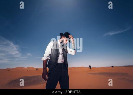 Mann mit Bart und Hut in den Dünen der Wüste von Marokko Stockfoto
