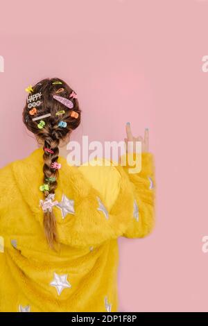 Teenager-Mädchen mit verschiedenen Haarnadeln in ihrem Zopf, so dass Horn Zeichen, Rückansicht Stockfoto