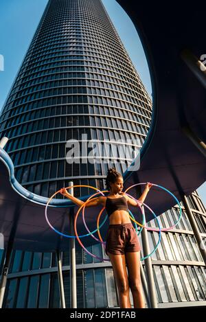 Sportliche Frau beim Training mit Kunststoffreifen vor dem Bürogebäude Stockfoto