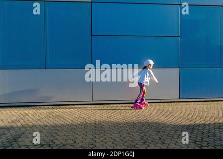 Kleines Mädchen mit Sicherheitshelm Inline Skating bei Sonnenlicht Stockfoto