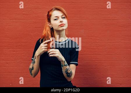 Portrait von Rothaarigen tätowierte Frau, die an einer Wand Stockfoto