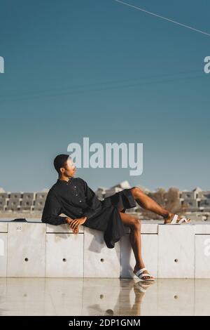 Junger Mann mit schwarzem Kaftan an einer Wand liegend Stockfoto