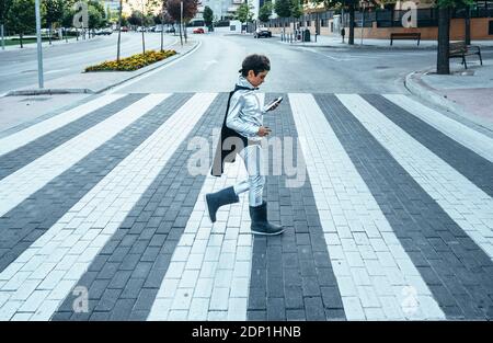 Portrait der Junge getarnt als Superheld Überqueren einer Straße die Stadt Stockfoto