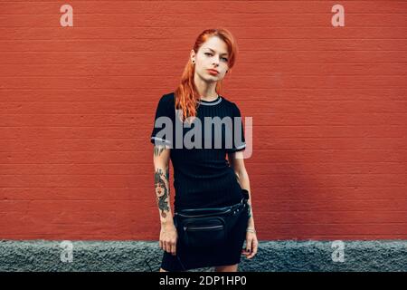 Portrait von Rothaarigen tätowierte Frau, die an einer Wand Stockfoto
