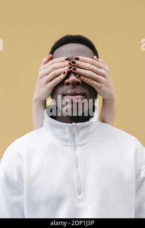 Die Hände der Frau bedecken die Augen des Mannes Stockfoto