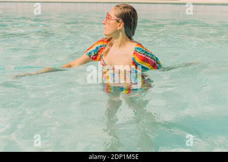 Gekleidete Frau, die sich im Pool entspannt Stockfoto