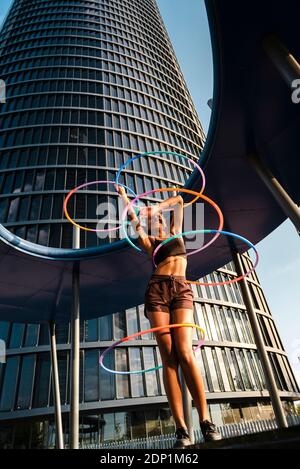 Fröhliche sportliche Frau mit Kunststoff-Reifen außerhalb des modernen Büros trainieren Gebäude Stockfoto