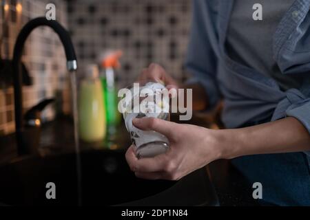 Seitenansicht der Ernte weiblich in legerer Kleidung waschen Glas Mit Schwamm und Waschmittel in der Küche zu Hause Stockfoto