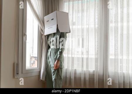 Frau trägt einen Karton auf dem Kopf mit gelangweilten Smiley suchen Aus dem Fenster Stockfoto