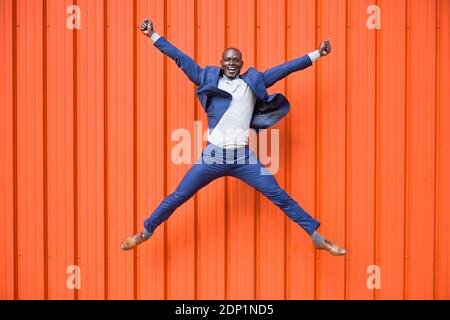 Gerne Unternehmer in der Luft vor orange Wand springen Stockfoto
